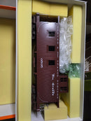 Burgundy model railroad caboose with windows, shown in open packaging.