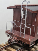Burgundy caboose end ladder and handrails detail beside open door.